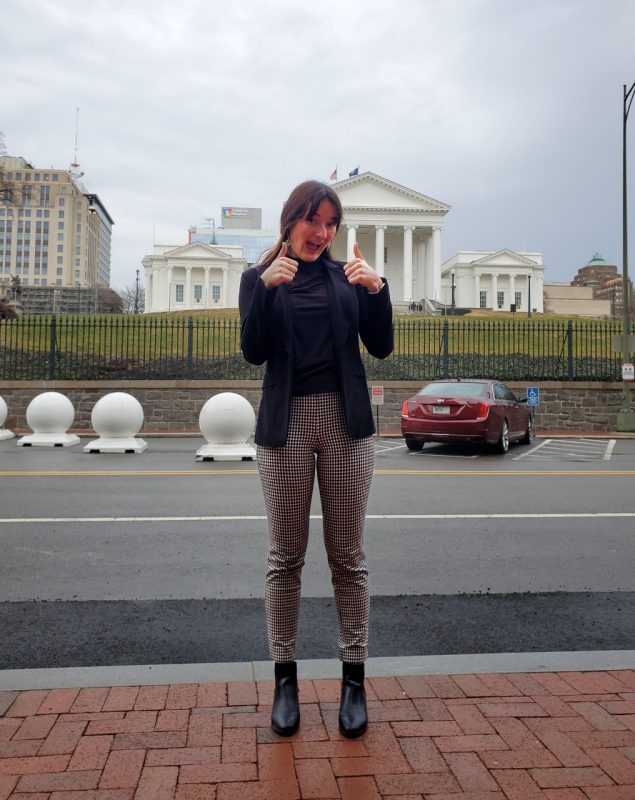 Student Amanda Ljuba makes a thumbs up sign in front of the Virginia State Capitol building.
