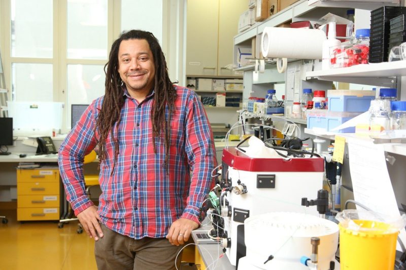 William "Bil" Clemons, Virginia Tech Biochemistry alumnus, stands in lab and smiles at camera