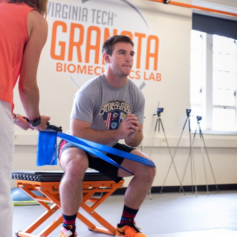 Male participant does a squat with a stretch band on his knee to test novel biofeedback intervention.