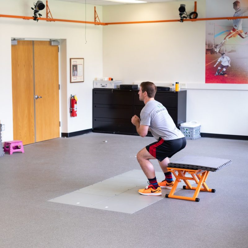 Photo of male participant squatting in the Granata Biomechanics Lab, as part of a biofeedback intervention clinical trial to test re-injury of ACL prevention