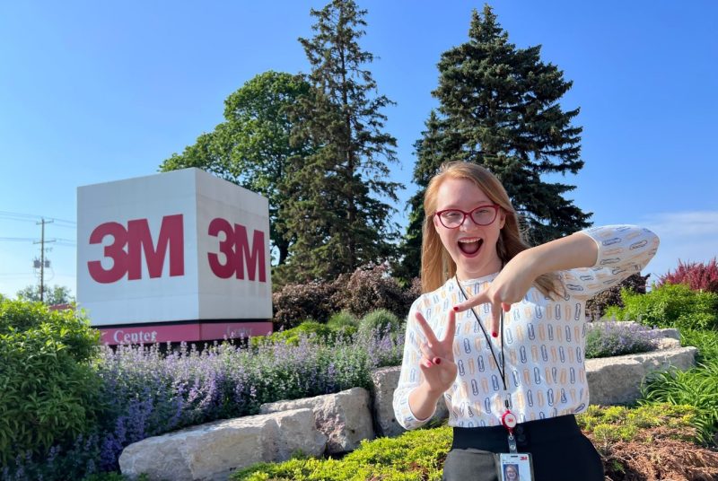 Rosa Williams stands in front of a sign with “3M.” 