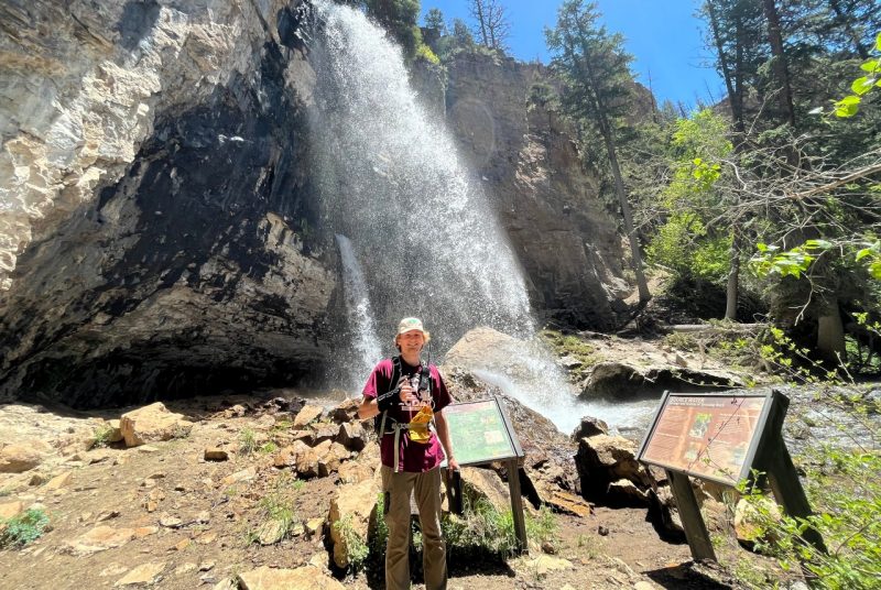 Noah Turner stands in front of a waterfall.