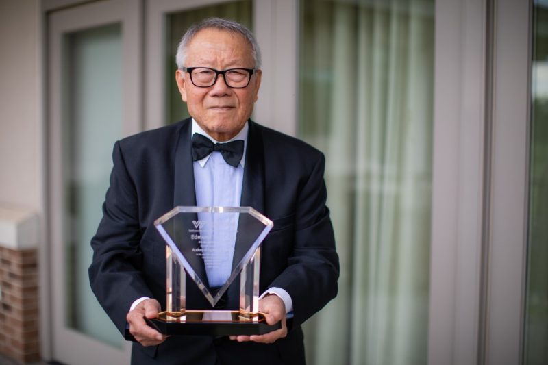 Edmund Chao smiles with his glass academy plaque