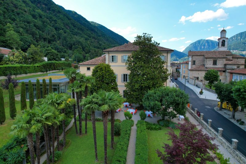 A villa and its lush courtyard in the foreground and large mountains beyond