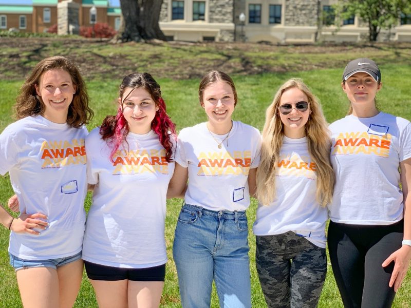 Five Virginia Tech women in AWARE t-shirts pose together.