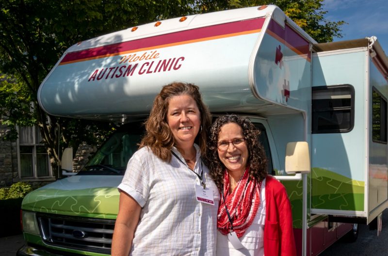 Two women stand in front of an RV.