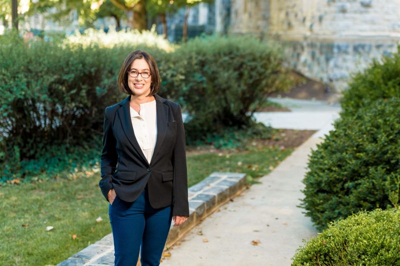 Estrella Johnson poses for a photo on campus, amongst bushes and Hokie stone