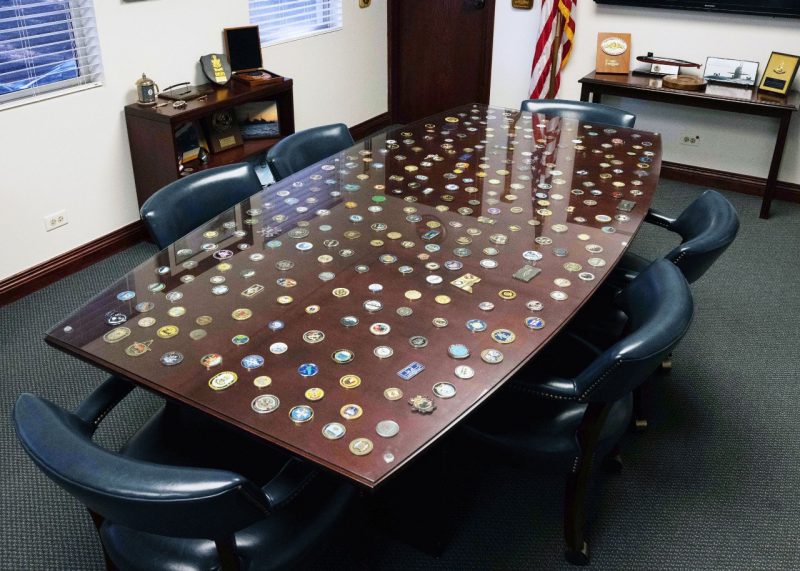 Challenge coins received by Rear Adm. Jeffrey Jablon cover the top of his office conference table. Photo by Amelia Umayam.