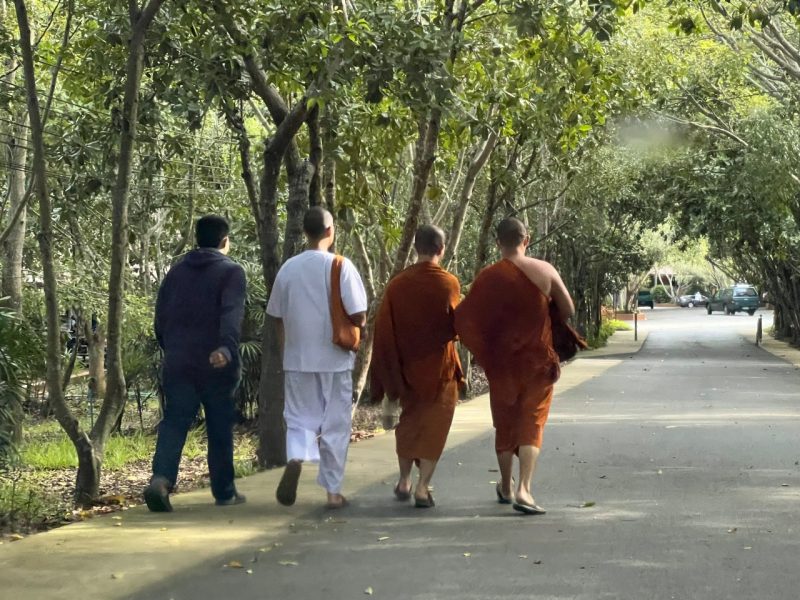 Sukthavorn, pictured in white clothing, walks to the temple with other monks a day after his disrobing ceremony.