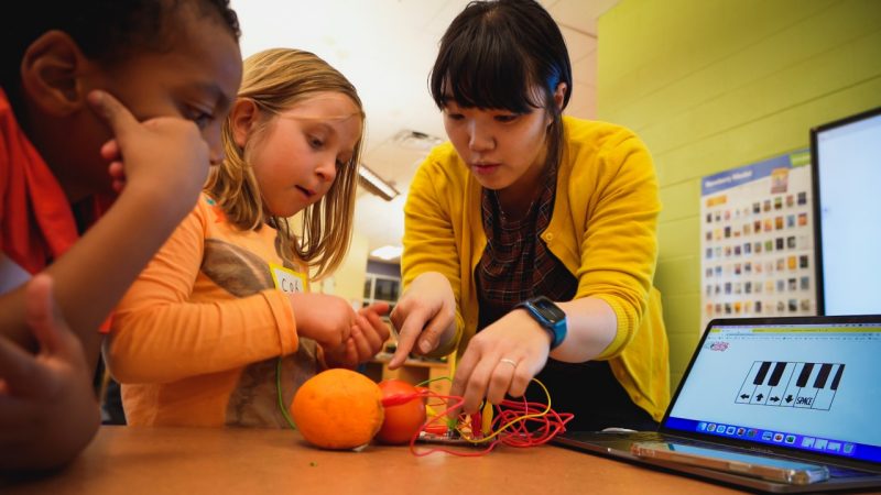 Koeun Choi, assistant professor in the Department of Human Development and Family Science, shows students how to hook up oranges and a tomato to a computer program that makes different sounds. 