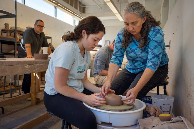 Martha Sullivan (at right) helps Laura Gahagan (at left) make a ceramic bowl from clay.