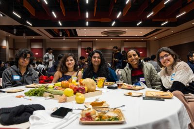 Five international students at a table in Squires Commonwealth Ballroom with a centerpiece of edible local produce.