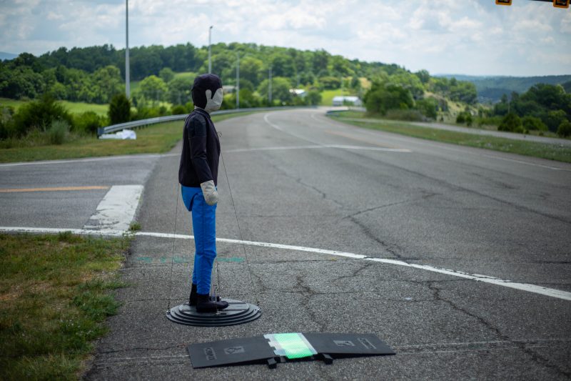 Pedestrian robot standing on the Virginia Smart Roads next to an LED pedestrian safety footboard