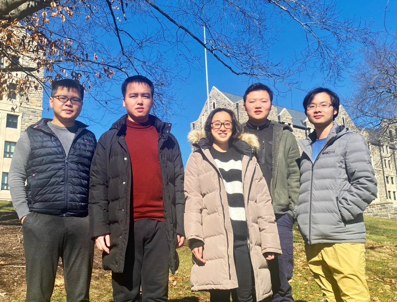 Group photo of four graduate students on the Alexa Prize SocialBot Grand Challenge team with faculty advisor Lifu Huang taken outdoors on the Virginia Tech Blacksburg Campus