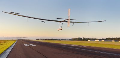 A solar battery-powered aircraft flying above a runway