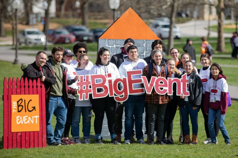 A large group of students holds a sign that says "#BigEvent" while standing on the Drillfield.