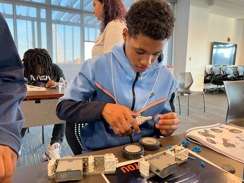 young student in blue shirt building a robot