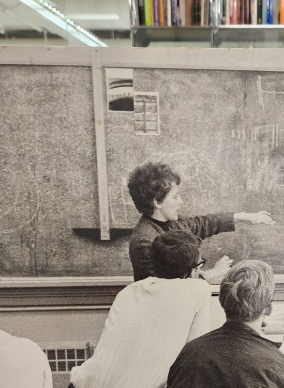 Lucy Ferrari teaching a class. Students looking at a blackboard.