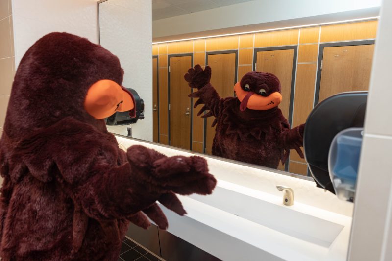 HokieBird does a style check in the mirror of Squires Student Center's renovated restroom.