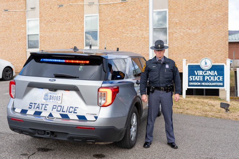 Virginia State Police trooper standing next to a new patrol vehicle with red and blue lights at the Salem District 6 Virginia State Police headquarters.