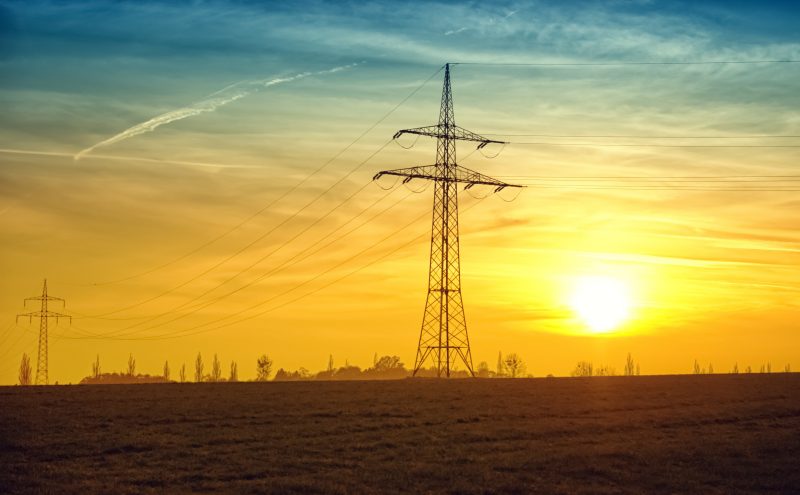 Image of the sun setting behind power lines. Photo courtesy Pexels/Pixabay.