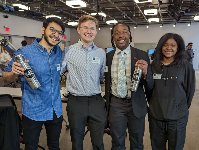 Four students holding CCI water bottles smile broadly at the camera