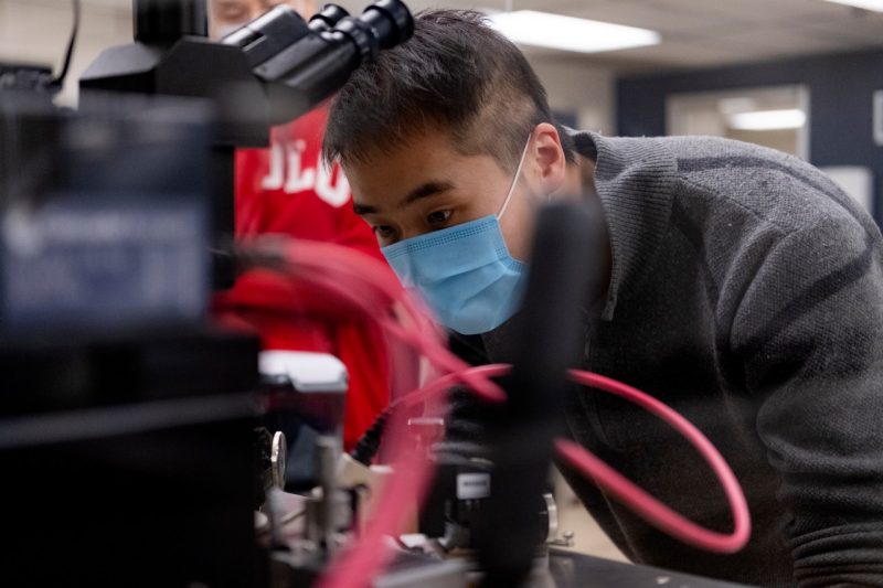 Photo shows a student examining a piece of equipment