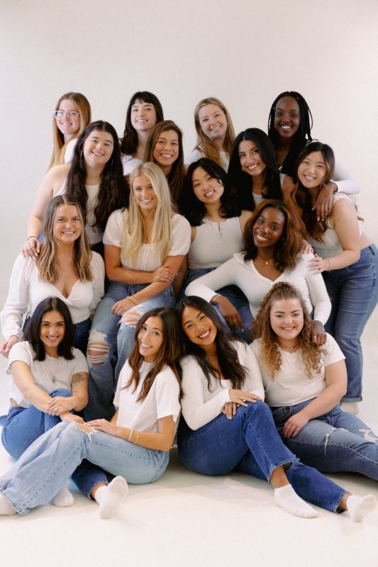 The 2023 cohort of Soulstice a cappella poses together for a photo in front of a white backdrop.