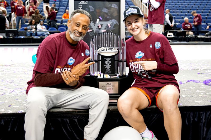 Women's basketball coach Kenny Brooks, left, poses with Taylor Geiman and the ACC Championship trophy that the Hokies won in early March. 