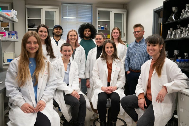 a group of people in lab coats, posing for photo in lab