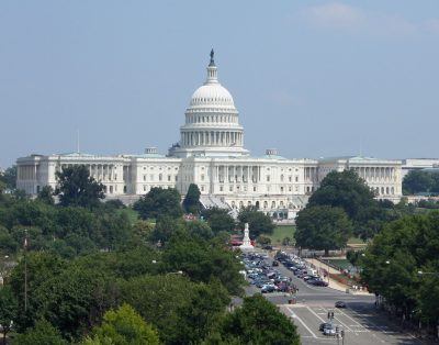 u.s. capitol building surrounded by trees and cars on road