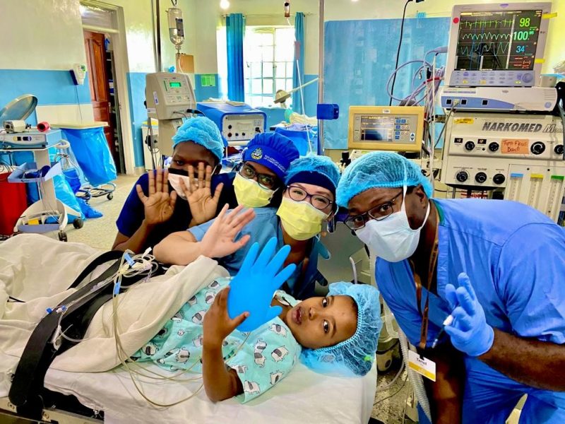 Joanna Kam and other health care professionals smile with a pediatric patient at a clinic in Kenya.