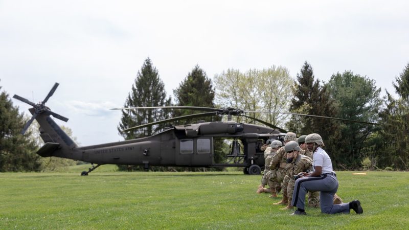 Melissa Gabriel (at right) kneels next to Army ROTC cadets as a Black Hawk helicopter lands.