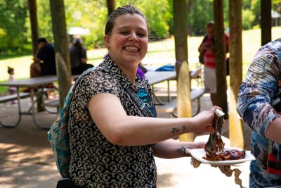 An employee smiling and holding a plate of food at the North Carolina Zoo. Photo by Darren Van Dyke for Virginia Tech Dining Services.