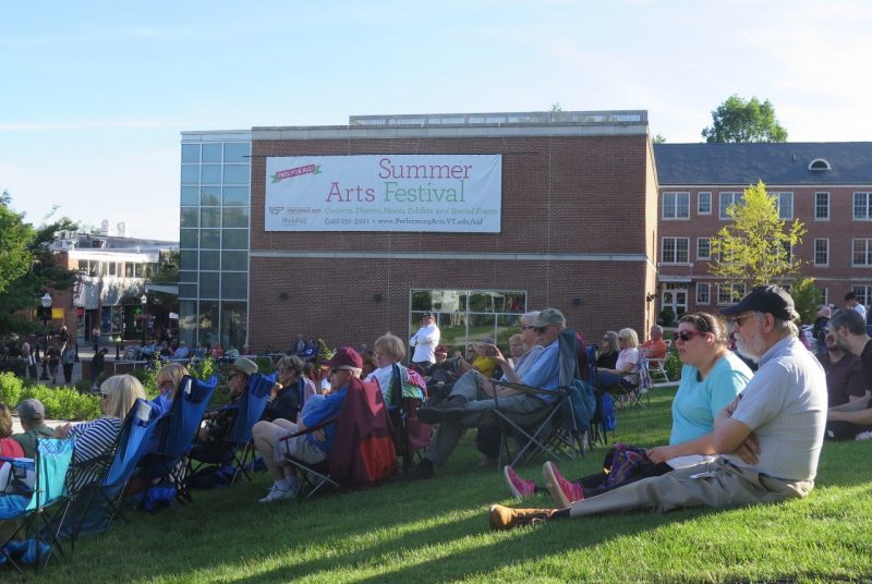 Summer Arts Festival attendees sit outdoors on Henderson lawn enjoying a concert.