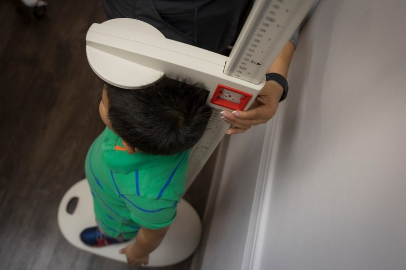 Little boy standing on a height and weight scale.