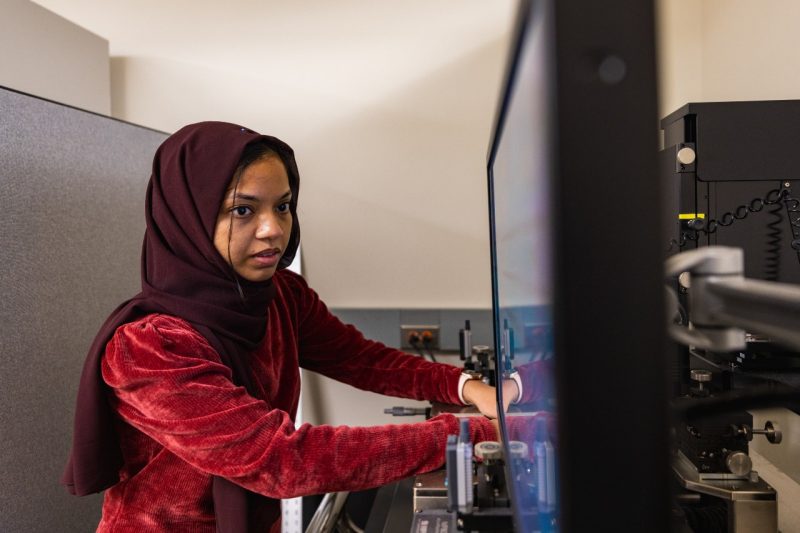 female engineering student works in electrical engineering lab while looking at screen for advancement of semiconductor work.