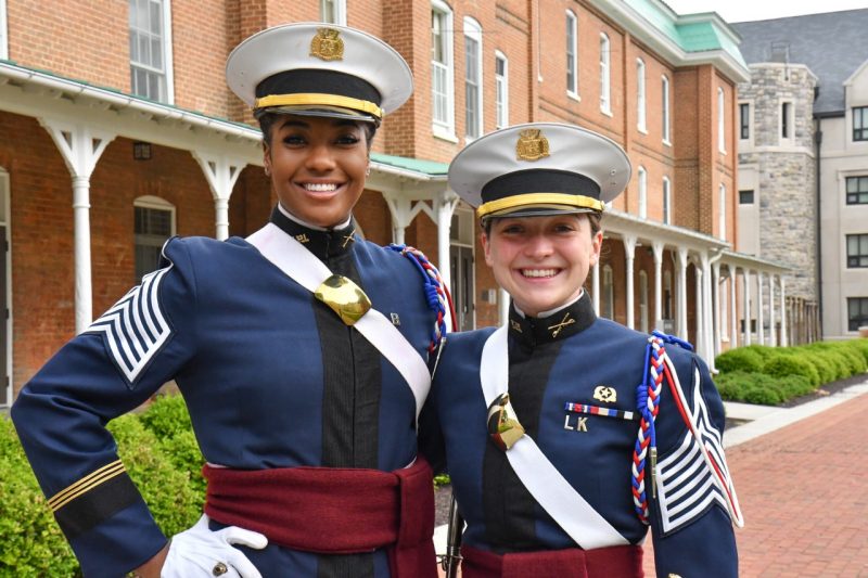 Brooke Johnson and Claire Seibel stand together on Upper Quad smiling. Both are wearing their dress uniforms.