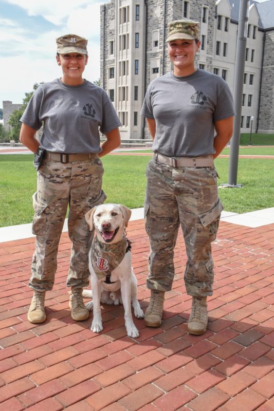 Two cadets stand with Growley II on Upper Quad.