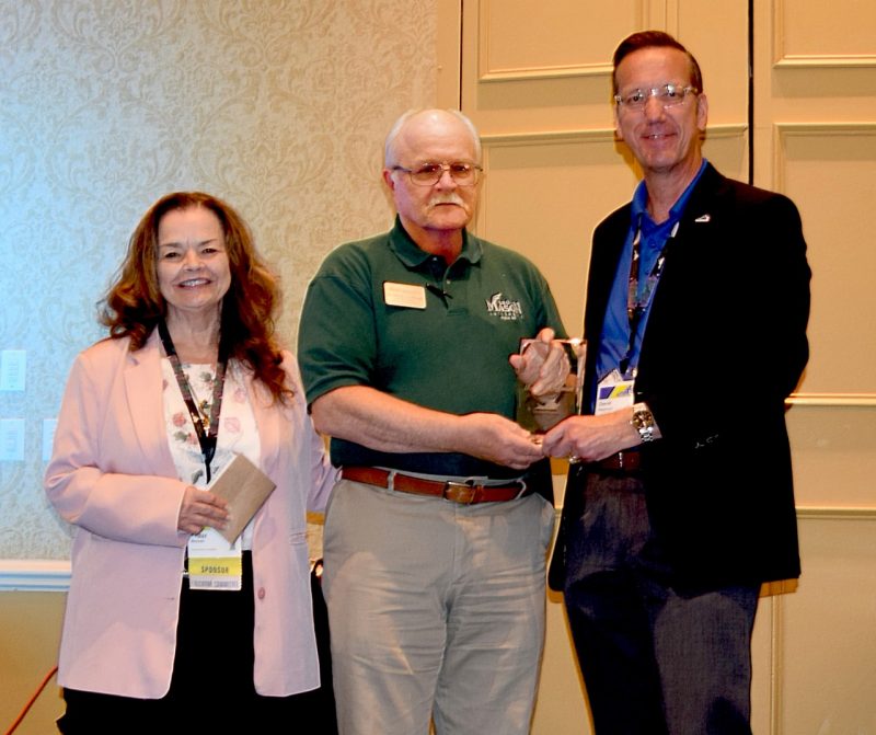 Peggy Brouse (at left) and David Raymond (at right) present Henry Coffman (at center) with the 2023 Virginia Cybersecurity Educator award. 