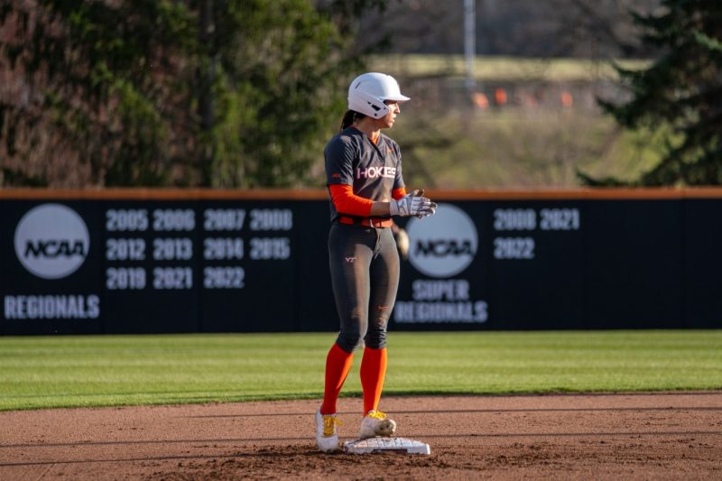 Emma Ritter in a black with orange accents softball uniform.