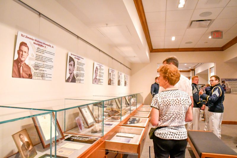 A line of glass cases display photos and mementos of Medal of Honor recipients from Virginia Tech. Boards hanging above the cases detail each recipient.