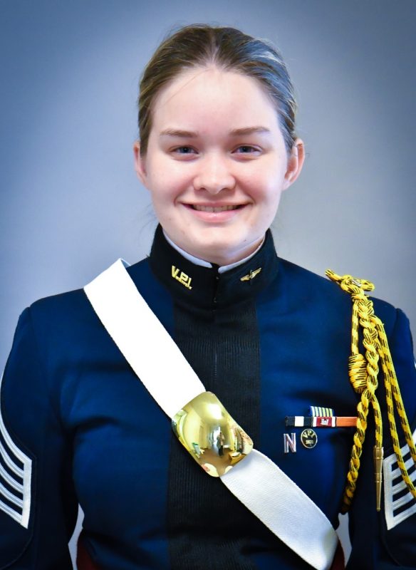 Portrait of Cadet McCullough. Her uniform blouse is blue and she is wearing a white crossbelt with a brass breastplate.