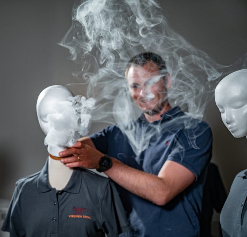 Researcher holds mannequin head while smoke fills the room
