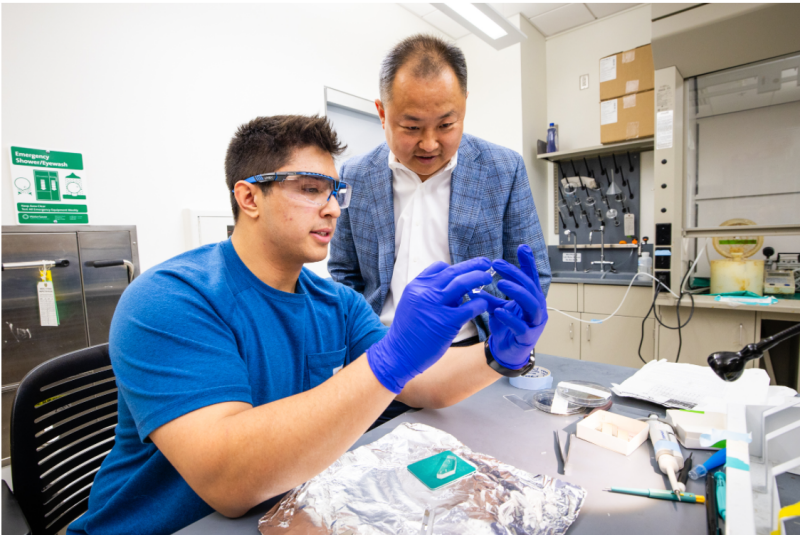 Chang Lu (right) and Ph.D. student Jacob Neide examine microfluidic device used in epigenomic assay