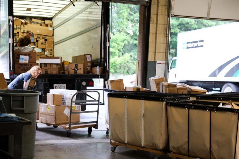 Mail Services using a cart to unload packages from an UPS truck