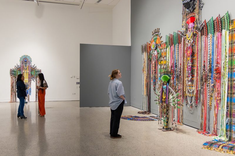 A woman views a large exhibit featuring a Native headdress in a gallery in the Moss Arts Center.