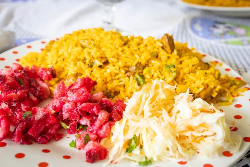 A plate of food filled with chicken rice, cabbage and red beets.
