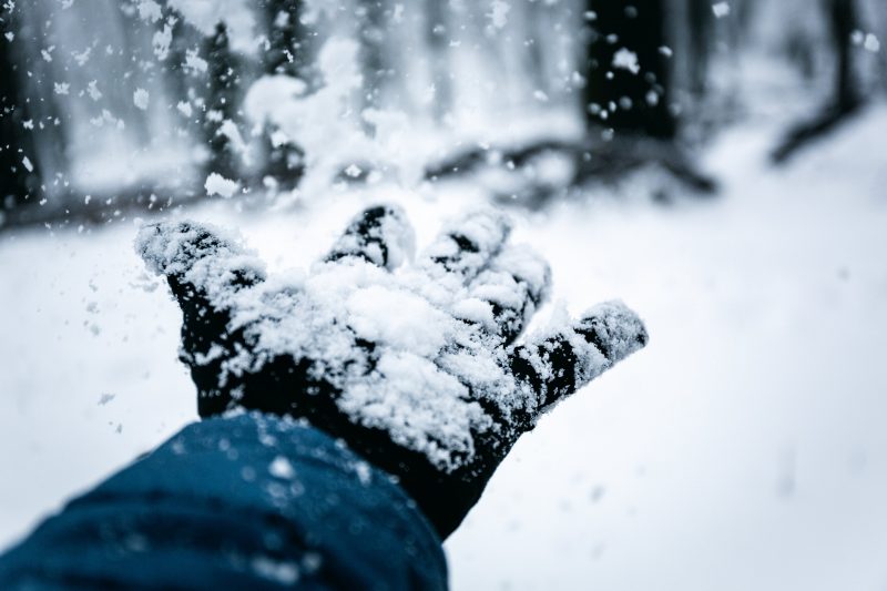 A gloved hand flinging snow. Image courtesy Pexels