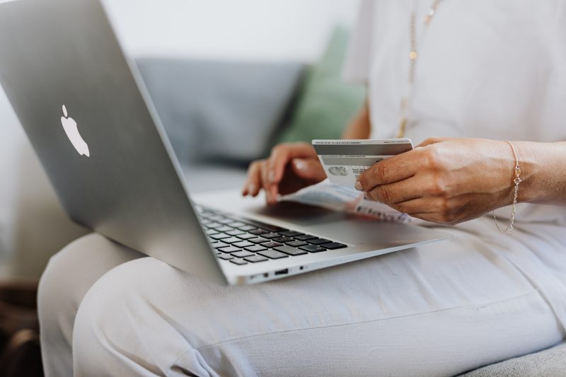 Person with lap top sitting on lap, holding credit card in hand